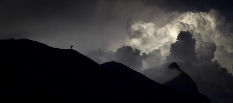 Photographie d’Alexandre Deschaumes – Col d’Anterne, massif du Haut-Giffre : silhouette d’un coureur sur la crête devant un cumulonimbus orageux, ambiance mystique et dramatique