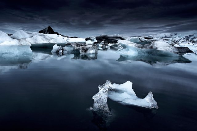 Jökulsárlón – Glace bleue sous la nuit islandaise Icebergs bleus dans la lagune glaciaire de Jökulsárlón en Islande, photographie nocturne en juin sous une lumière sombre et mystérieuse